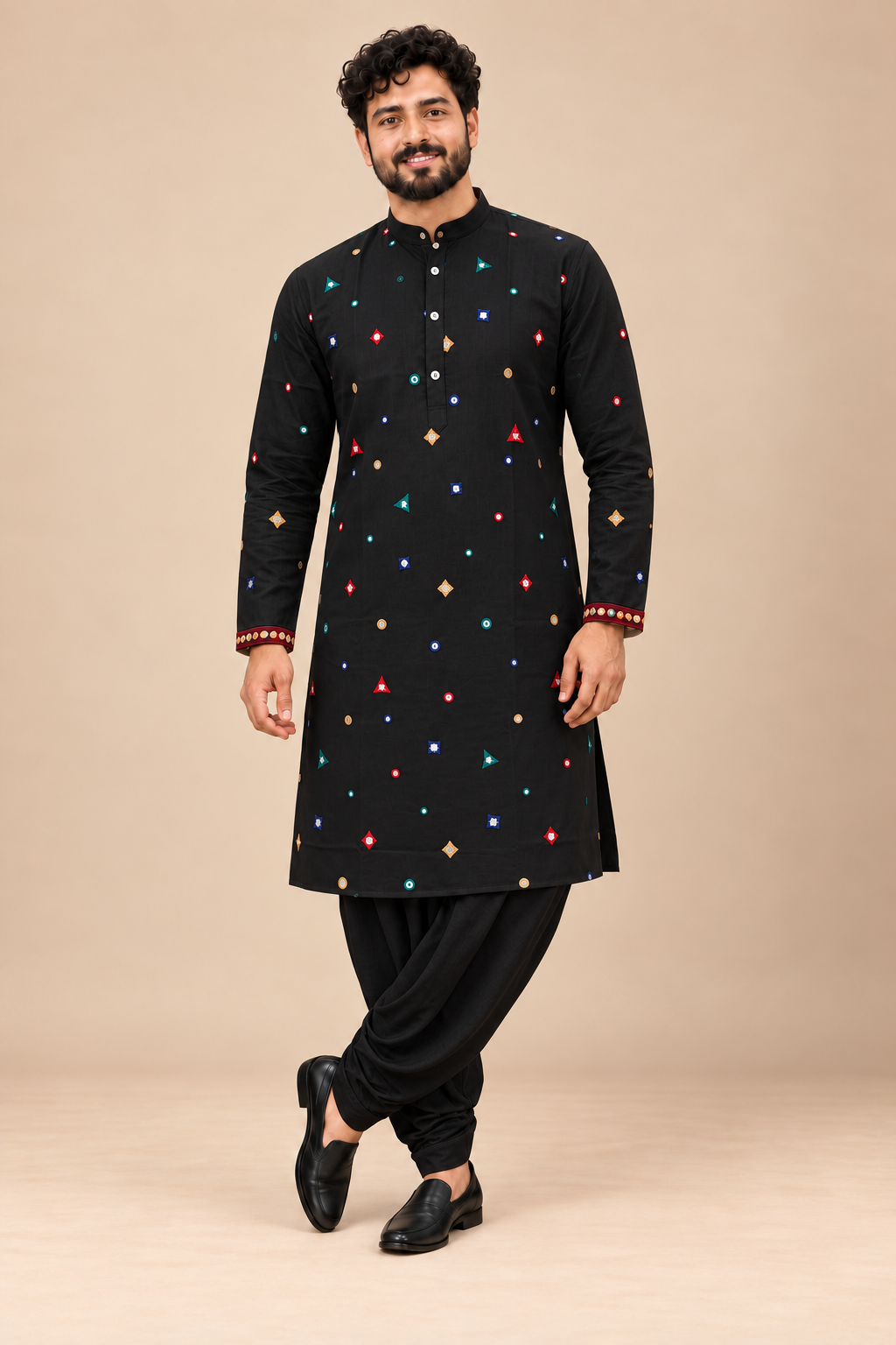 Indian model wearing black kurta with colorful geometric embellishments and black stitched dhoti against a beige background